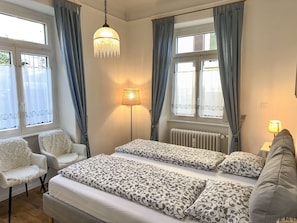 A bedroom with a bed, two chairs, a lamp, and a window with curtains. - Villa Clara by Interhome (Minusio)