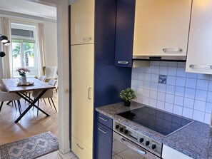 A modern kitchen with a built-in oven, a dining area with a table and chairs, and a view of the outdoors through a window. - Villa Clara by Interhome (Minusio)