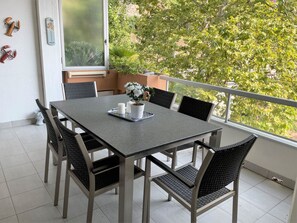 A dining area with a table and chairs, a potted plant, and a view of greenery. - Dolce Vita by Interhome (Brissago)