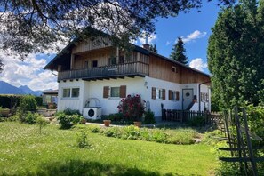 Ein zweistöckiges Chalet mit Balkon, umgeben von einem gepflegten Garten und einem Holzzaun.