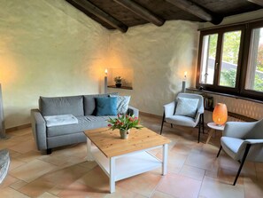 A cozy living room with a sofa, armchair, and coffee table, featuring a potted plant and a lamp. - Casa Girasol by Interhome (Cavigliano)