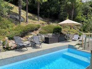 Ein Schwimmbad mit Liegestühlen und Grillplatz.