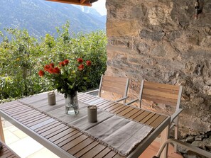 Une table en bois ornée d’un vase de roses rouges, de deux bougies et offrant une vue sur les montagnes.