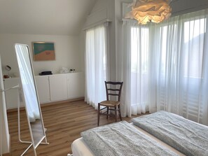 Une chambre à coucher avec un lit, une chaise, un bureau avec un miroir et un tableau accroché au mur.