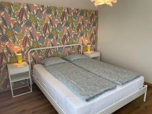 Ein Schlafzimmer mit einem Bett, zwei Nachttischen und einer Wand mit einem Blumenmuster.