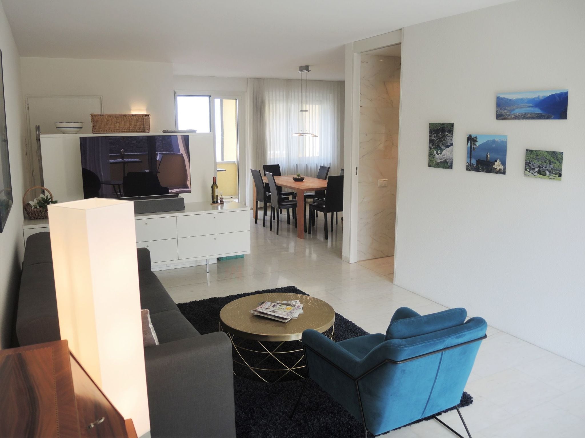 A modern living room with a sofa, a coffee table, and a dining area with a table and chairs.