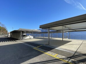 Ein überdachter Parkbereich mit Blick auf Berge und ein Gewässer.