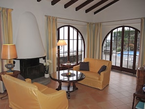 A living room with a fireplace, two sofas, a coffee table, and large windows with curtains. - Casa Mirandola by Interhome (Brissago)