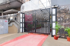 A gated entrance with a red carpet, a metal gate, and a potted plant. - Super Townhouse Hotel All In One  (Barasat)