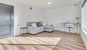 A modern living room with a grey sofa, a small round table, and a desk with a chair. - Modern 2 bed townhome just minutes from downtown and SLC airport (Salt Lake City)