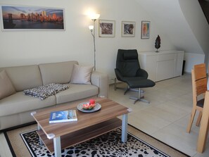A living room with a sofa, a chair, a coffee table with a book, and a lamp. - Residenza Sabrina Duplex by Interhome (Ascona)