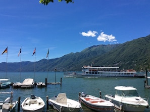 A marina with various boats docked, a large ferry, and a mountainous backdrop. - Residenza Sabrina Duplex by Interhome (Ascona)