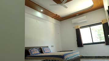 A bedroom with a bed, a ceiling fan, an air conditioning unit, and a window with curtains.