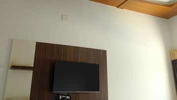 Une pièce dotée d’un ventilateur de plafond, d’un téléviseur à écran plat fixé au mur et d’un plafond avec des poutres apparentes.