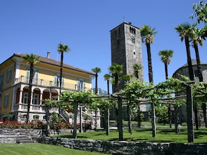 A historic building with a tower, surrounded by palm trees and a well-maintained garden. - Azzurro by Interhome (Minusio)