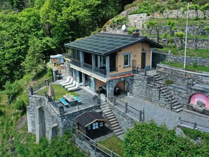 Ein zweistöckiges Haus mit Balkon, Steinmauern und einem Solardach.