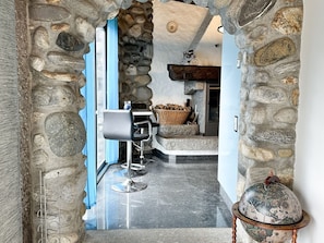 Ein steinerer Bogen führt zu einer modernen Küche mit Steinwand, einer Bar mit Hockern und einem Globus auf einem Ständer.