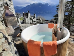 Ein Whirlpool mit Holzverkleidung, einer Steinwand und Blick auf die Berge im Hintergrund.