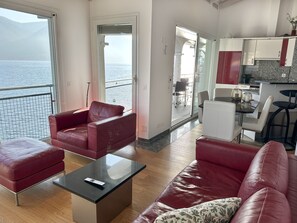 Ein modernes Wohnzimmer mit einem roten Ledersofa, einem schwarzen Couchtisch und Meerblick durch große Fenster.