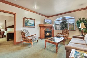 A living room with a fireplace, two floral armchairs, a sofa, and a television. - 2BR, 2BA villa with full kitchen in Midway's Zermatt Resort.-2030-2 (Midway)