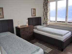 Ein Schlafzimmer mit zwei Betten, einem Schminktisch und einem Fenster mit Bergblick.