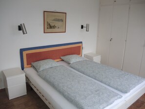 A single-bed room with a wooden headboard, two bedside tables, a white wardrobe, and a framed picture on the wall. - La Civetta by Interhome (Brissago)