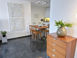 A modern kitchen with a dining area, featuring a wooden table and chairs, a decorative vase, and a tiled floor. - Apartment Siesta by Interhome (San Nazzaro)