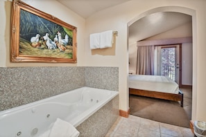 Ein Badezimmer mit einer großen Badewanne, einem Hühnerbild und einem Bett im angrenzenden Zimmer.
