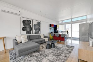 A modern living room with a grey sectional sofa, a coffee table, and abstract art on the wall. - Manhattan Style 2BR with insane City views in vibrant Cape Town (Cape Town)