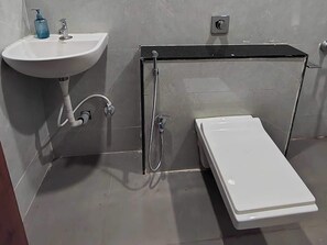Un baño con un lavabo blanco, un cabezal de ducha de mano y un inodoro blanco.