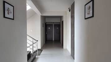 A hallway with a staircase on the left, a door at the end, and framed pictures on the walls.