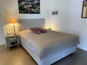 A bedroom with a bed, nightstands, a lamp, a wall art piece, and a mirror. - Luxury Apartment by Interhome (Minusio)
