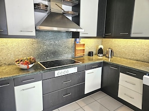 A modern kitchen with a black and white color scheme, stainless steel appliances, and a granite countertop. - Casa Lydia by Interhome (Brione sopra Minusio)