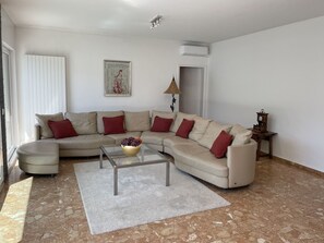 A living room with a beige sofa, a glass coffee table, and a red and beige patterned throw pillow. - Villa Genovese by Interhome (Minusio)