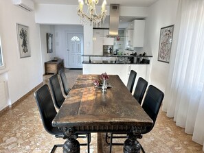 En matplats med ett långt träbord, svarta stolar och en kristallkrona.