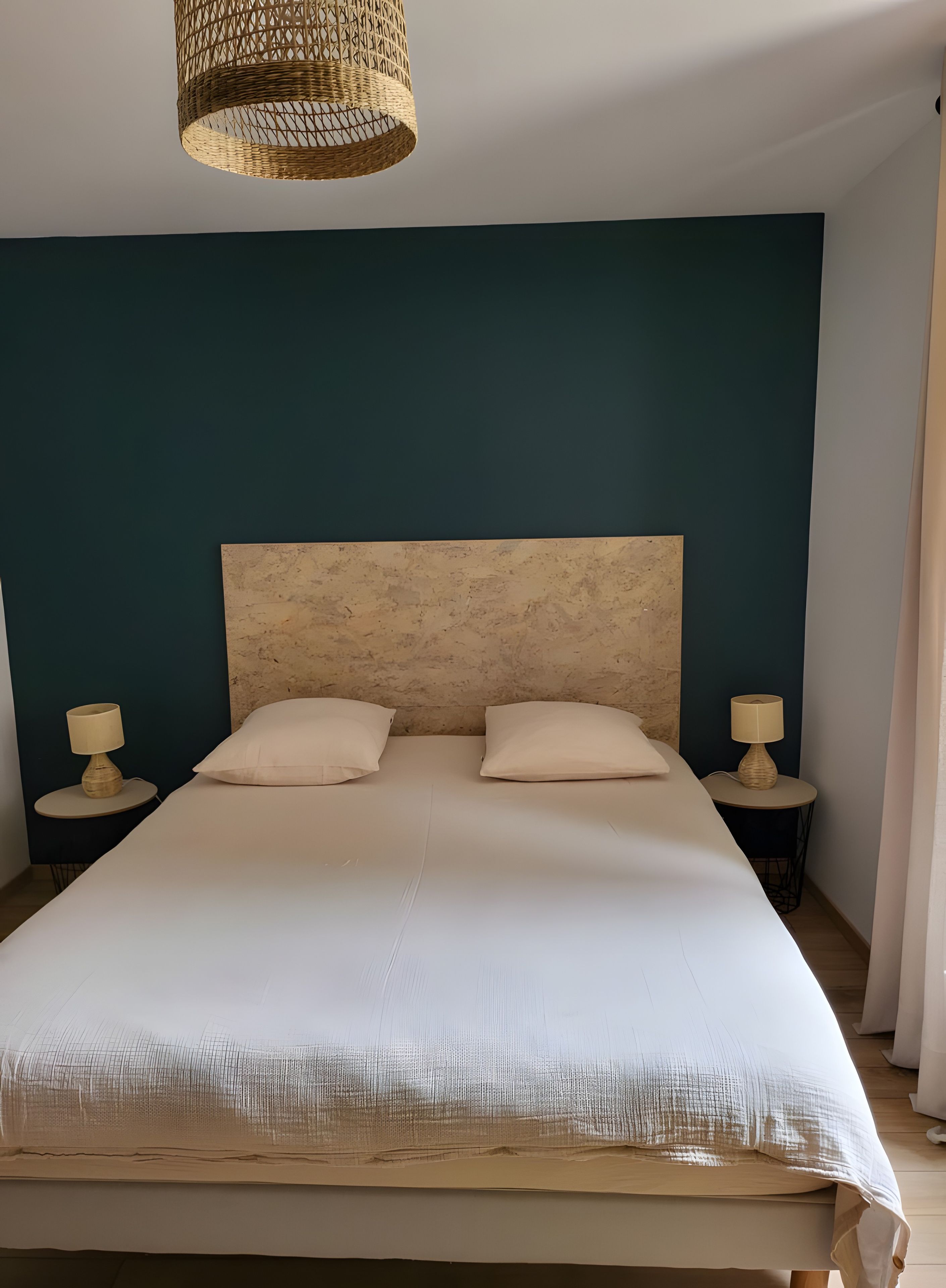 Ein Schlafzimmer mit einem großen Bett, zwei Nachttischen mit Lampen und einer gewobenen Deckenleuchte.