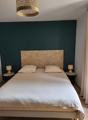 Ein Schlafzimmer mit einem großen Bett, zwei Nachttischen mit Lampen und einer gewobenen Deckenleuchte.