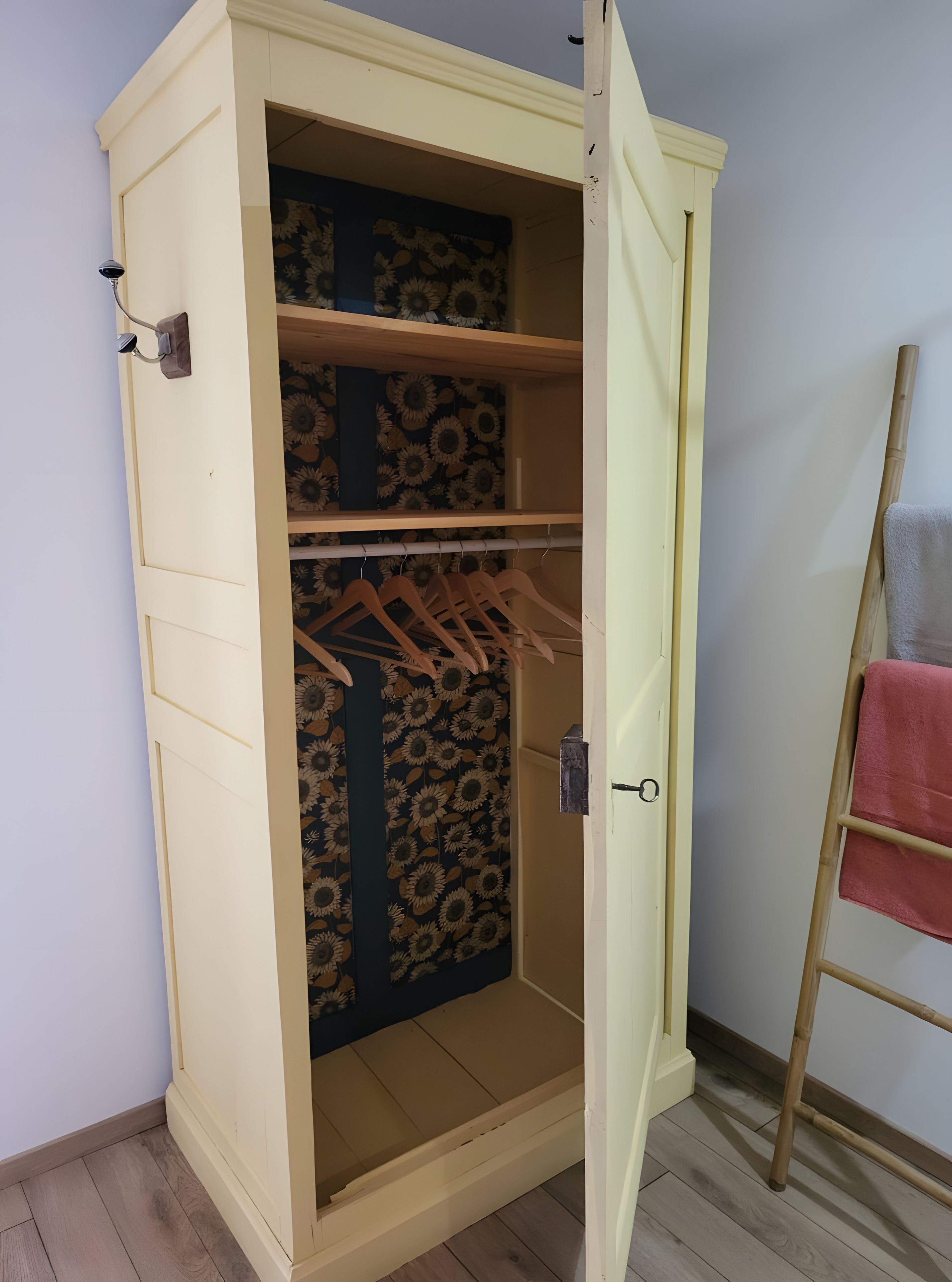 Un placard avec plusieurs étagères et une tringle pour suspendre les vêtements, une échelle en bois et une serviette sur le sol.