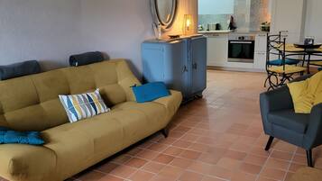 A living room with a sofa, a coffee table, and a dining area with chairs.
