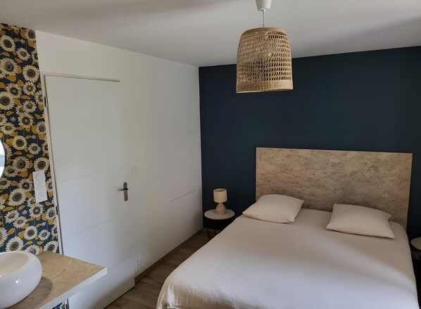 Camera da letto con un letto, un comodino, una lampada e una porta con carta da parati floreale.