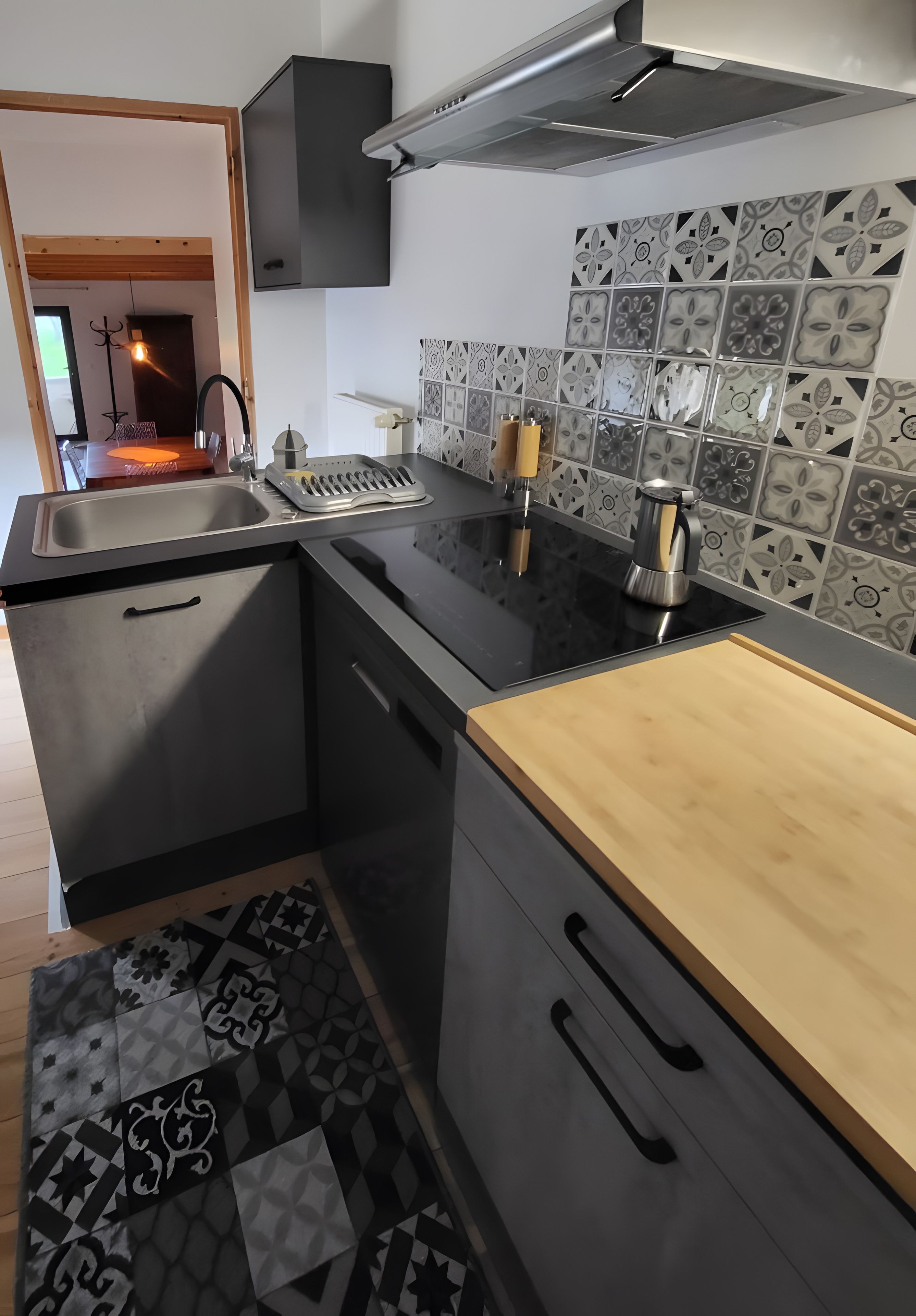 A modern kitchen with a black countertop, stainless steel appliances, and patterned backsplash.