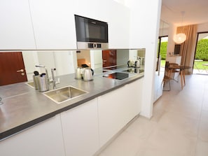 A modern kitchen with a Bosch microwave, stainless steel appliances, and a large window. - Residenza Sabrina App. 09 by Interhome (Ascona)