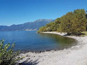 A clear lake with a rocky shore, surrounded by trees and mountains in the background. - Residenza Sabrina App. 09 by Interhome (Ascona)