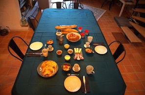 Ein Esstisch mit Geschirr, Besteck und verschiedenen Speisen, der darauf hindeutet, dass eine Mahlzeit vorbereitet oder serviert wird.