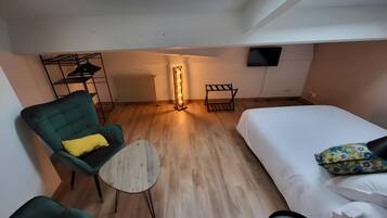 Een moderne hotelkamer met dakraam, een bed, een groene fauteuil, een klein tafeltje en een radiator.