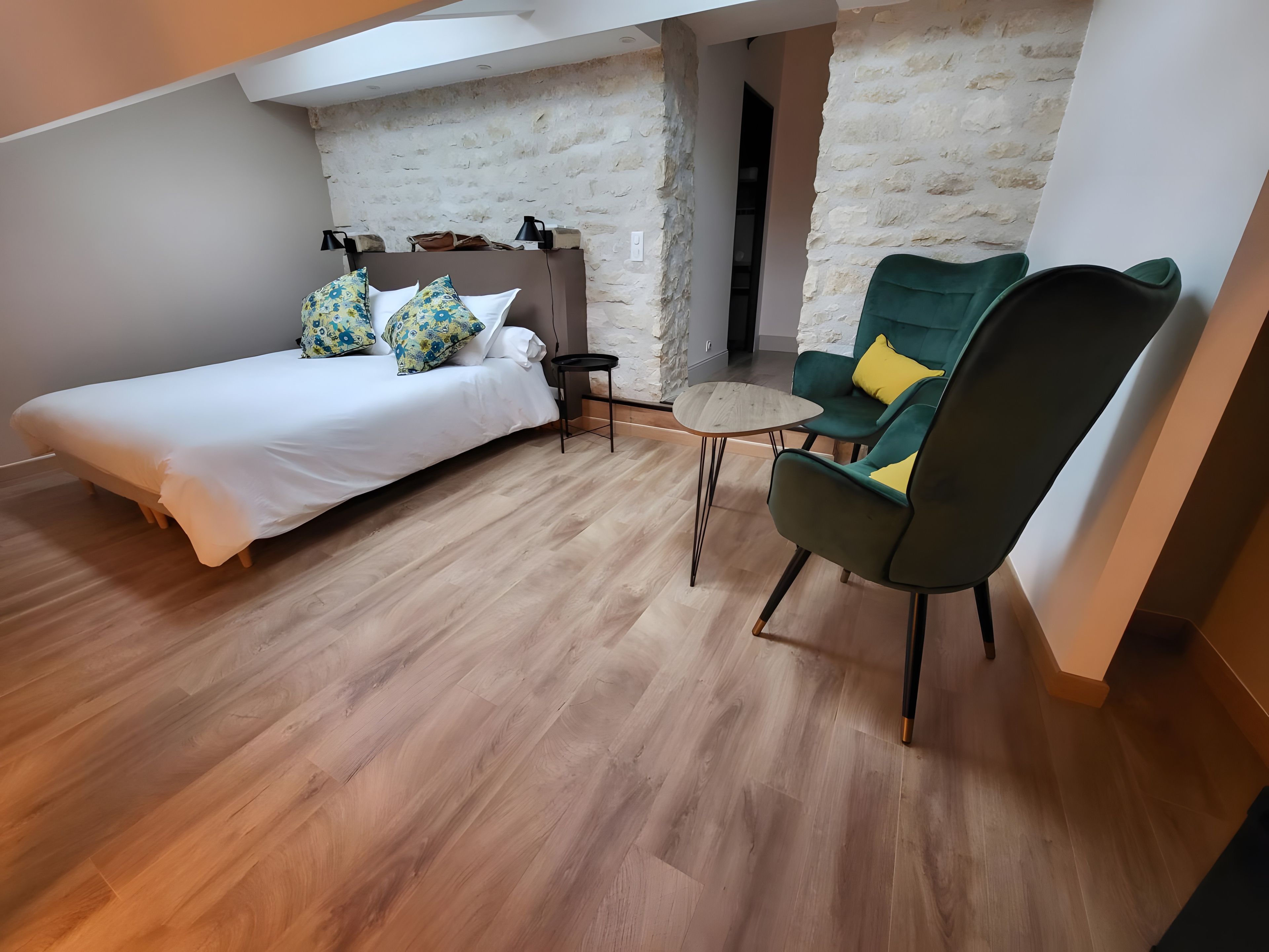 Een slaapkamer met een bed, een stoel en een klein tafeltje.