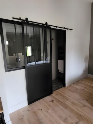 Ein Zimmer mit einer Schiebetür, Holzboden und einer weißen Wand.