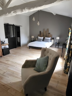 Una camera da letto con un letto, comodini, una sedia e un soffitto in legno.