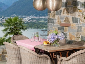 A wicker dining table with a pink tablecloth, a vase of flowers, and a bowl of fruit. - Casa Gioia by Interhome (Gerra)