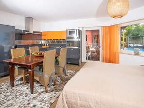 Une chambre d’hôtel moderne dotée d’un coin repas, d’une kitchenette et offrant une vue sur une piscine extérieure.